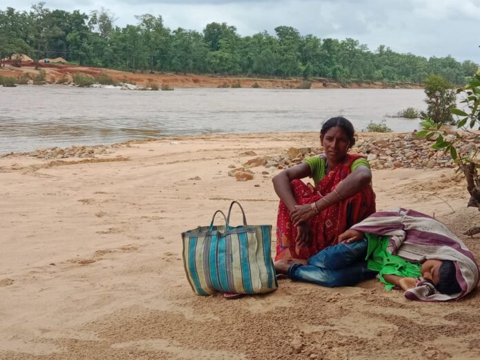 No bridge, only a small boat for support: A mother waited with her sick son in her arms.